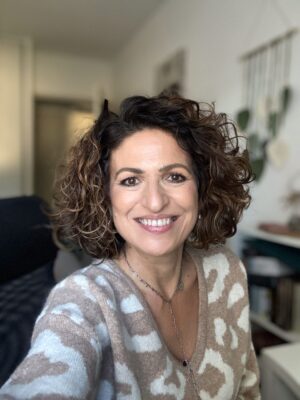 Portrait souriant de Christine dans un intérieur lumineux et apaisant.